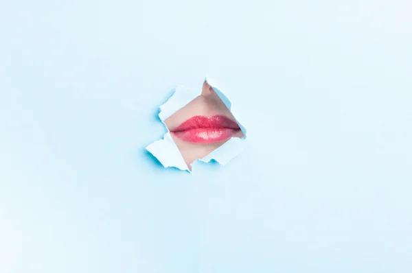 Ελκυστική γυναίκα στόμα φορώντας κραγιόν μέσα από την τρύπα σχισμένο χαρτί — Φωτογραφία Αρχείου