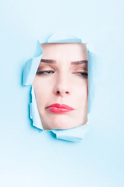 Beautiful woman doubt face with makeup thru torn cardboard — Stock Photo, Image