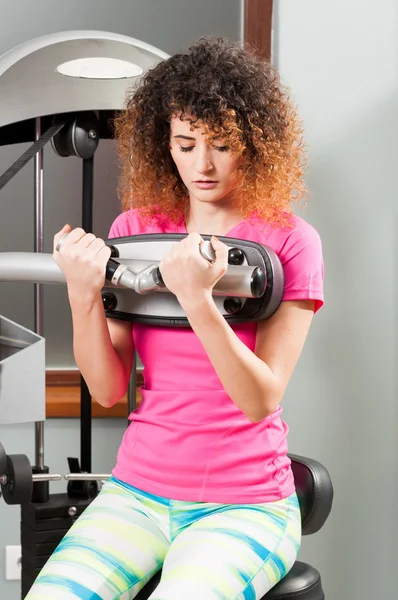Mujer haciendo ejercicio bíceps con máquina de ejercicio — Foto de Stock