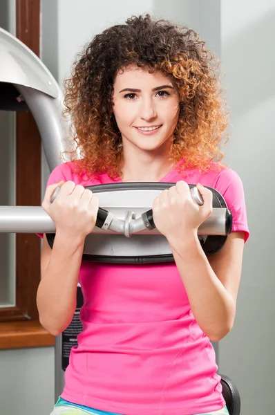 Atrakcyjna młoda kobieta uśmiechając się podczas ćwiczeń w siłowni — Zdjęcie stockowe