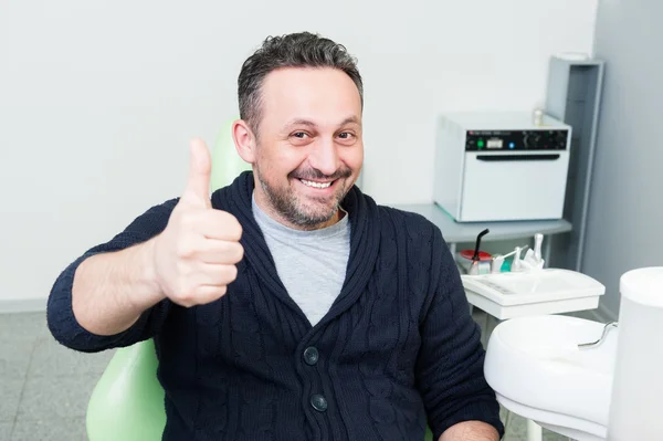 Sonriente paciente sentado feliz en la silla del dentista — Foto de Stock