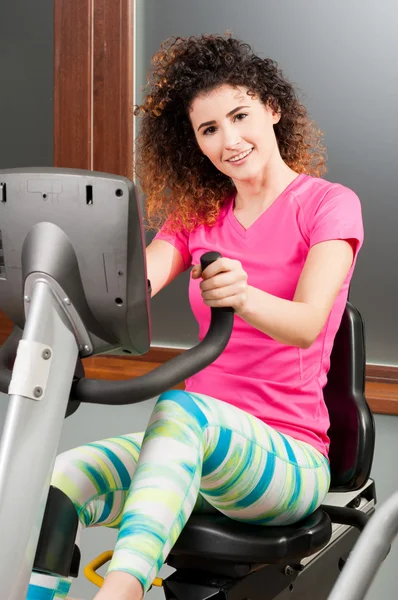 Beautiful smiling woman spinning the stationary bicycle — Stock Photo, Image