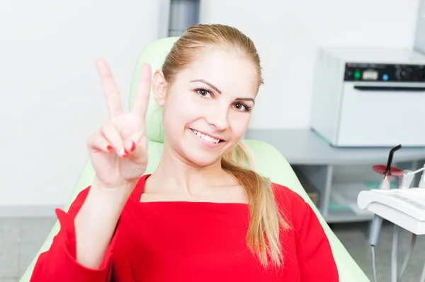 Молодая и красивая пациентка у стоматолога демонстрирует победный жест — стоковое фото