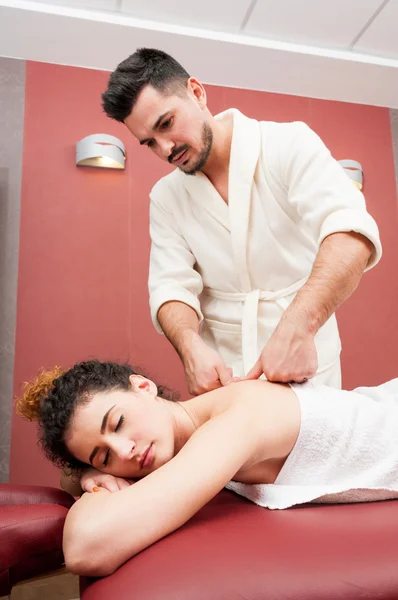 Young male masseur giving a back massage to attractive woman — Stock Photo, Image