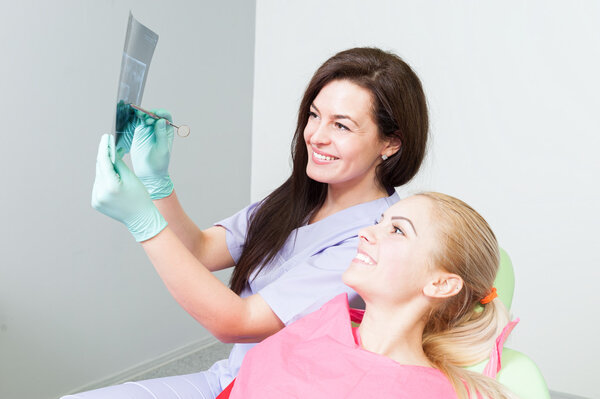 Врач-стоматолог и пациент, осматривающий рентген зубов
