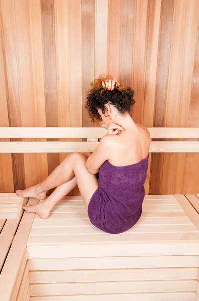Mulher tendo um cuidado corporal envolto em toalha na sauna — Fotografia de Stock