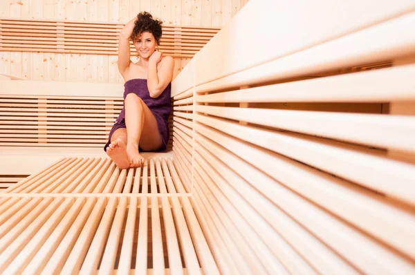 Молода усміхнена жінка розслабляється в дерев'яній сауні — стокове фото