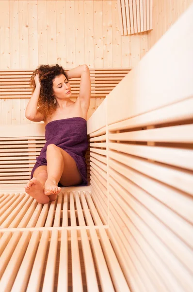 Кучеряве молода жінка відпочиває і насолоджується сауною — стокове фото