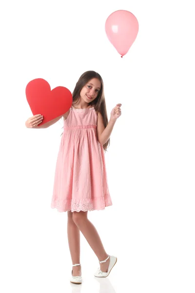 Belle fille tenant une forme de coeur rouge et un ballon rose — Photo