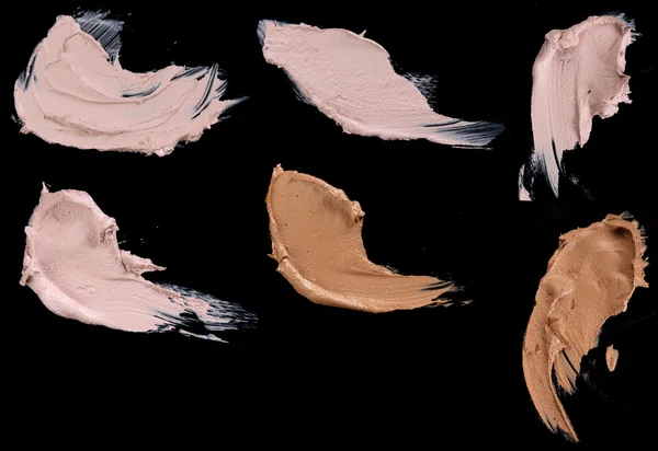 Various make up liquid powder strokes on black background — Stock Photo, Image