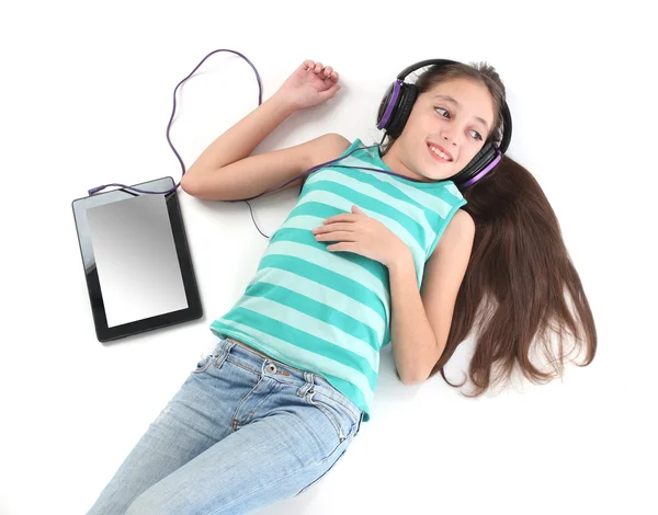 Hermosa chica pre-adolescente acostada en el suelo con una tableta — Foto de Stock