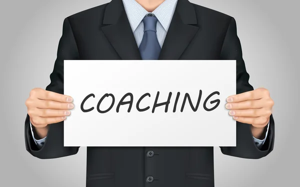 Hombre de negocios sosteniendo cartel coaching — Vector de stock