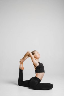 Siyah elbiseli kadın yoga pozu veriyor.