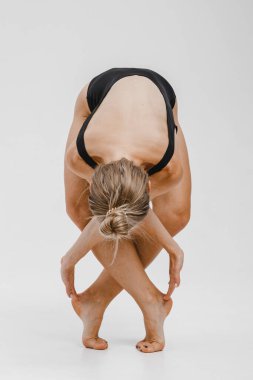 Siyah elbiseli güzel sarışın kadın yoga pozu veriyor.