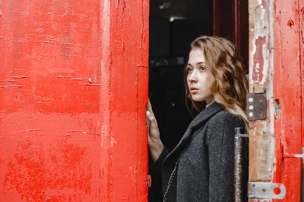 Όμορφη Σγουρή Κοπέλα Στέκεται Κοντά Στην Κόκκινη Πόρτα Μαύρο Παλτό — Φωτογραφία Αρχείου