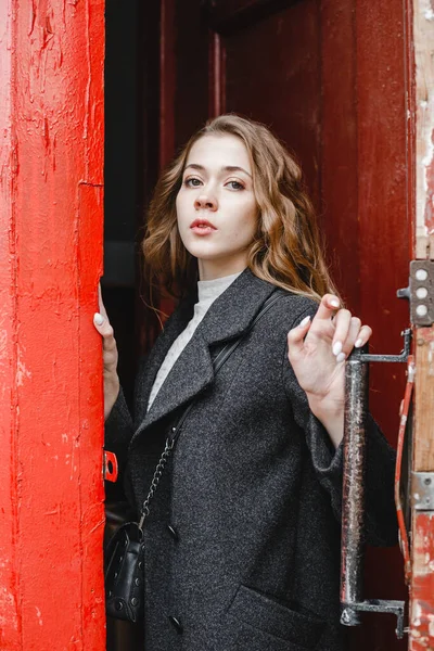 Güzel Kıvırcık Kız Kırmızı Kapının Yanında Duruyor Siyah Ceketli — Stok fotoğraf