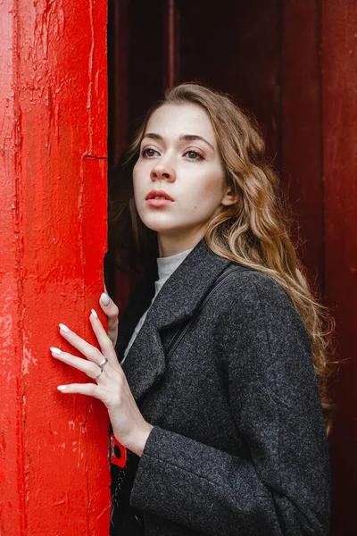 Linda Menina Encaracolado Fica Perto Porta Vermelha Casaco Preto — Fotografia de Stock