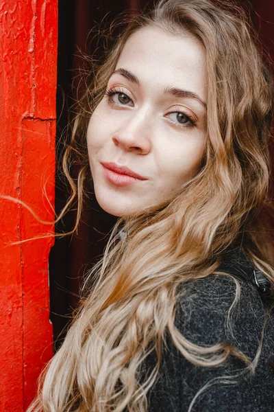 Beautiful Curly Girl Stands Red Door Black Coat — Stock Photo, Image