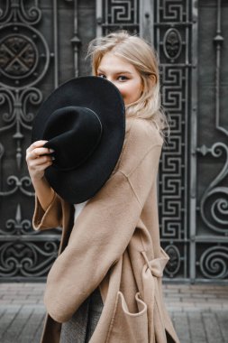 Kahverengi ceketli, siyah şapkalı, gülümseyen, üzgün