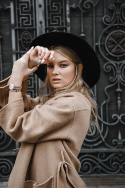 Kahverengi ceketli, siyah şapkalı, gülümseyen, üzgün