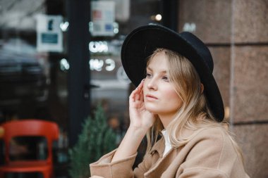 Kahverengi ceketli, siyah şapkalı, gülümseyen, üzgün