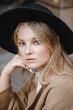 Kahverengi ceketli, siyah şapkalı, gülümseyen, üzgün