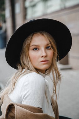 Kahverengi ceketli, siyah şapkalı, gülümseyen, üzgün