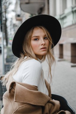 Kahverengi ceketli, siyah şapkalı, gülümseyen, üzgün