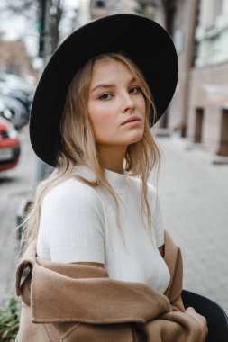 Kahverengi ceketli, siyah şapkalı, gülümseyen, üzgün
