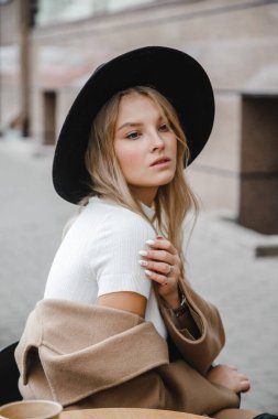 Kahverengi ceketli, siyah şapkalı, gülümseyen, üzgün