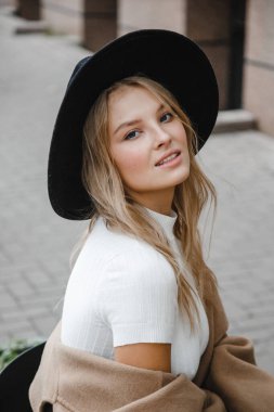 Kahverengi ceketli, siyah şapkalı, gülümseyen, üzgün