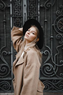 Kahverengi ceketli, siyah şapkalı, gülümseyen, üzgün