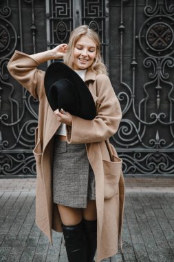 Kahverengi ceketli, siyah şapkalı, gülümseyen, üzgün