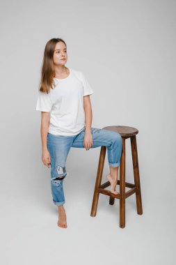 Model testleri. Uzun saçlı güzel bir kız sandalyeye yakın duruyor ve poz veriyor.