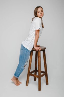 Model testleri. Uzun saçlı güzel bir kız sandalyeye yakın duruyor ve poz veriyor.