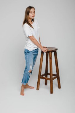 Model testleri. Uzun saçlı güzel bir kız sandalyeye yakın duruyor ve poz veriyor.