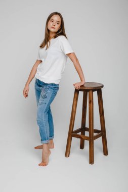 Model testleri. Uzun saçlı güzel bir kız sandalyeye yakın duruyor ve poz veriyor.