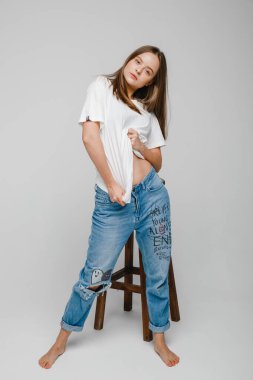 Model testleri. Uzun saçlı güzel bir kız sandalyeye yakın duruyor ve poz veriyor.