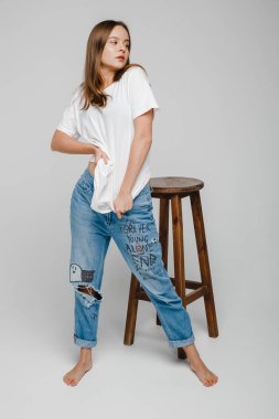 Model testleri. Uzun saçlı güzel bir kız sandalyeye yakın duruyor ve poz veriyor.