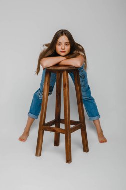 Model testleri. Uzun saçlı güzel bir kız sandalyeye yakın duruyor ve poz veriyor.