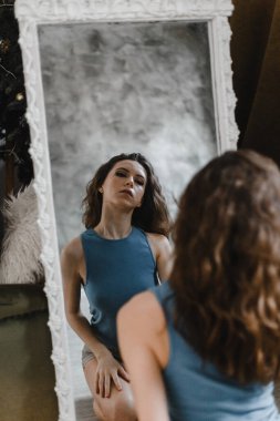 Şort ve mavi tişörtle poz veren güzel kıvırcık kız.