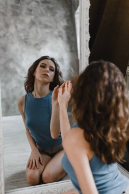 Şort ve mavi tişörtle poz veren güzel kıvırcık kız.