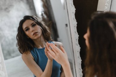 Şort ve mavi tişörtle poz veren güzel kıvırcık kız.