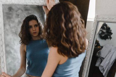 Şort ve mavi tişörtle poz veren güzel kıvırcık kız.