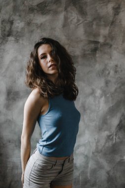 Şort ve mavi tişörtle poz veren güzel kıvırcık kız.