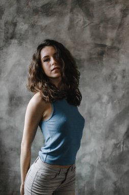 Şort ve mavi tişörtle poz veren güzel kıvırcık kız.