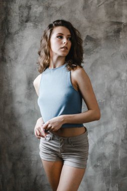 Şort ve mavi tişörtle poz veren güzel kıvırcık kız.