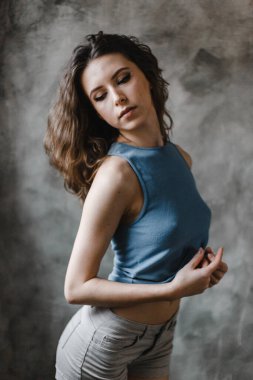 Şort ve mavi tişörtle poz veren güzel kıvırcık kız.