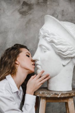 Güzel kıvırcık kız beyaz alçı kafayı öpüyor