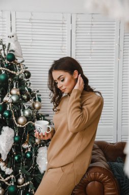 Bej pijamalı güzel bir kız elinde beyaz bardakla kahveyle